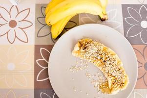 Un alto ángulo de vista de un plátano en rodajas cubierto con avena y miel foto