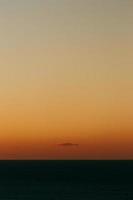 A massive horizon with an orange gradient and a single cloud with copy space photo