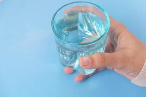 mano sosteniendo un vaso azul sobre un fondo azul
