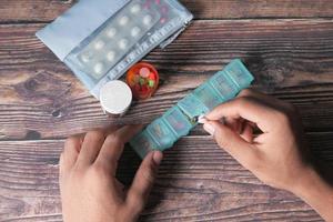 Top view of man's hands taking medicine from a pill box photo