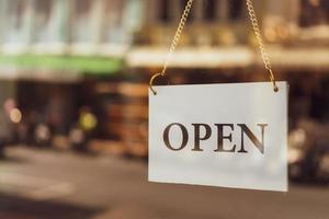 A business sign that says open hanging on door at entrance photo