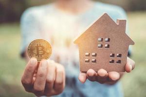 Copyspace model of a little house and a symbol of cryptocurrency held by a woman photo