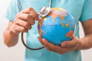 Doctor holding a stethoscope to a world globe concept photo