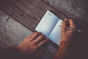 Woman hand writing down in small memo notebook photo