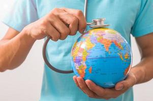 Doctor holding a stethoscope to a world globe concept photo