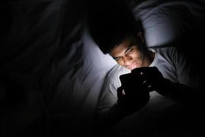 Man using smart phone in bed photo