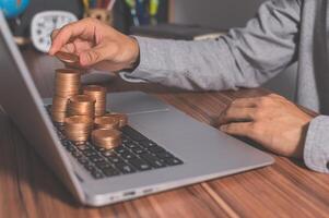 A man is putting coins on a laptop photo
