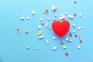 Heart shape with pills on blue background photo