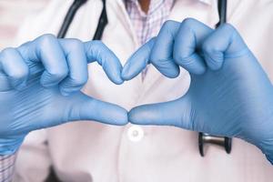 Hands wearing gloves holding heart shape photo