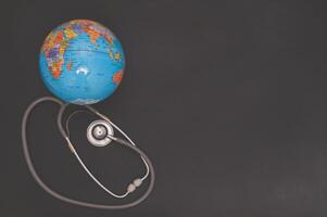 Small world globe with stethoscope on black background photo