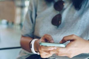 Woman using a smartphone at cafe shop with sunlight photo