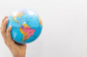 Hand holding small earth globe on white background
