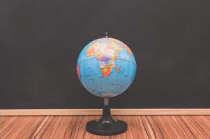 A globe on a stand in front of a blackboard photo