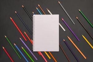 Notebook with pencils on black background photo