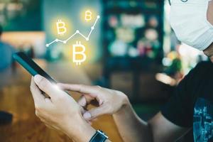 persona que usa un teléfono inteligente con iconos de bitcoin foto