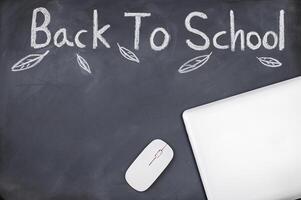Back to school concept with laptop and mouse on blackboard photo