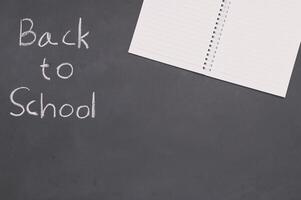 Back to school concept with notebook and pen on blackboard photo