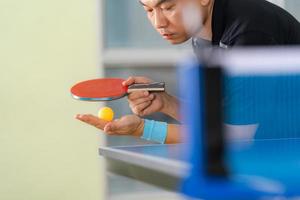 Male playing table tennis with racket and ball in a sport hall