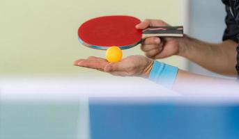 Macho jugando tenis de mesa con raqueta y pelota en un pabellón deportivo foto