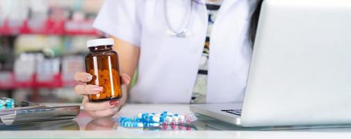 The pharmacist holds a bottle of medicine in the pharmacy photo