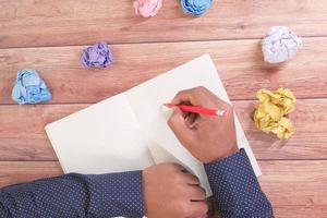 Man writing in a journal with crumpled paper photo