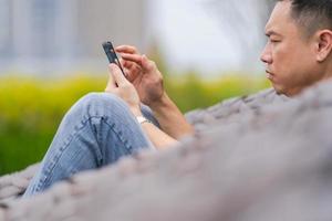Hombre relajándose y usando el teléfono inteligente en el parque de la ciudad