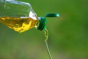 Vegetable oil pouring from bottle with nature background photo