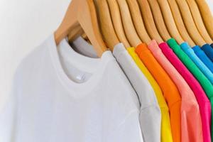 Cerca de camisetas en perchas, antecedentes de prendas de vestir foto