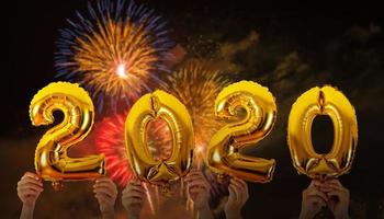 Hands holding 2020 number balloons with fireworks background photo