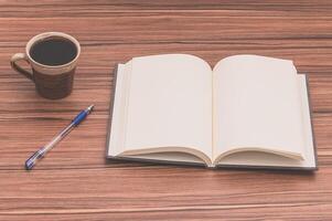Open book, pen and coffee on wooden table photo