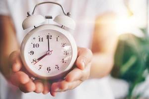 Selective focus of alarm clock with nature bokeh background photo