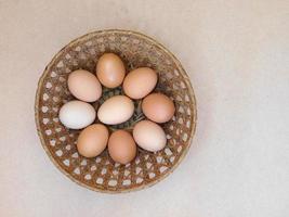 Brown eggs in a wicker basket on a light table background photo