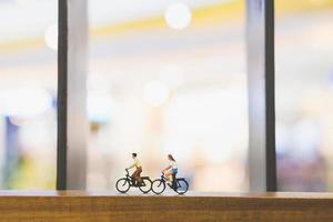 Viajeros en miniatura con bicicletas en un puente de madera