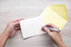 Male hands writing on an empty card on a wooden table photo