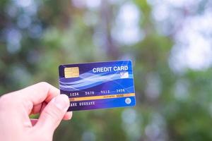 A hand holding a credit card with bokeh background, financial freedom concept photo