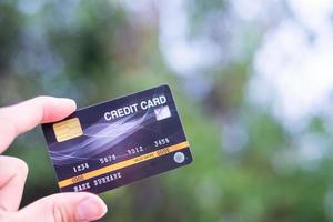 A hand holding a credit card with bokeh background, financial freedom concept photo