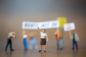 Multitud de manifestantes en miniatura levantando sus manos y gritando sobre un fondo de madera foto