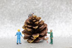 Trabajadores en miniatura preparando un cono de pino navideño, navidad y feliz año nuevo concepto foto