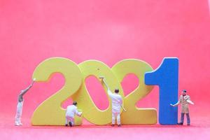 Trabajadores en miniatura pintando el número 2021, feliz año nuevo concepto foto