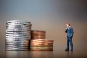 Miniature small businessmen standing with a stack of coins, business growth concept photo