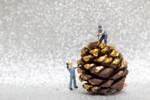 Miniature workers preparing a Christmas pine cone, Christmas and Happy New Year concept photo
