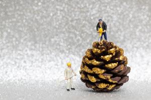 Miniature workers preparing a Christmas pine cone, Christmas and Happy New Year concept photo