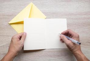 Male hands writing on an empty card on a wooden table photo