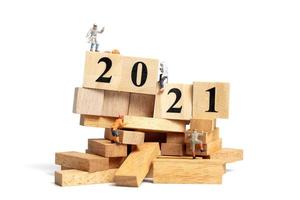 Group of miniature people climbing up on wooden cubes with numbers 2021 photo