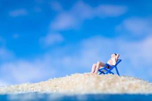 Gente en miniatura tomando el sol en la playa, concepto de verano foto