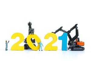 Miniature workers building wooden numbers 2021, Happy New Year concept photo