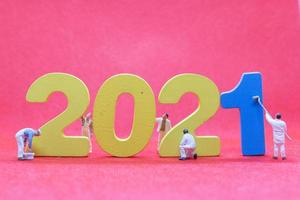 Miniature workers painting the number 2021, Happy New Year concept photo