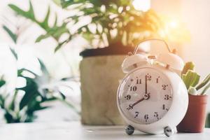 Selective focus of alarm clock showing 8 o'clock with nature bokeh background photo