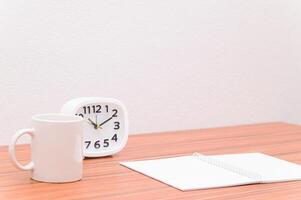 A white mug and a clock on a table photo