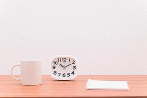 A coffee mug and a clock on a desk photo